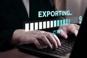 Technology professional uses a laptop on a table with an exporting data load bar waiting on a digital display. Concept of data processing and reporting using office programs photo