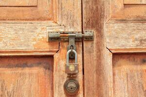 la puerta de madera marrón tiene una llave y una cerradura y una manija para cerrar la puerta para evitar que los ladrones y ladrones roben sus pertenencias y objetos de valor. es una antigua puerta de madera foto