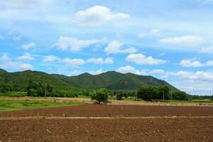 Farmers plow the soil with tractors to prepare the next season's crops and optimize the soil for cultivation in a setting with blue skies and mountains as a beautiful backdrop. photo