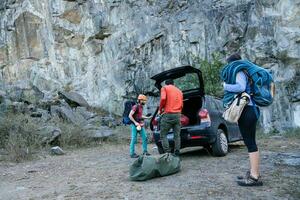 Group of young people at the foot of the mountain unloading rock climbing gear. photo