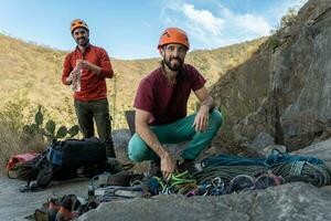 sonriente hombres preparando alpinismo engranaje. foto