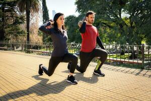 Man and woman training with weights in a city square. photo