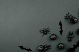 Happy halloween flat lay composition with black pumpkins, spiders and bats on dark background. Holiday concept. Top view. Copy space. photo