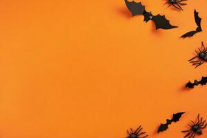 Happy halloween flat lay mockup with black spiders and bats on orange background. Holiday concept composition. Top view. Copy space. photo