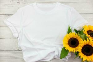 White womens cotton T Shirt mockup with sunflowers on white wooden background. Design t shirt template, print presentation mock up. Top view flat lay. photo