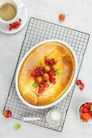 Homemade casserole with cottage cheese, semolina, fresh red currant and strawberry on light gray background. Top view. photo