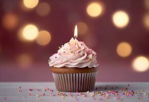 Birthday cupcake with a candle, pink cream and festive tinsel decoration on bright background with copy space. Generated AI. photo