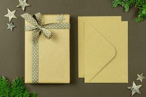 Christmas wrapped vintage gift box with ribbon, envelopes, decoration and thuja branches on dark background. Holiday flat lay mockup. Top view. Copy space. photo