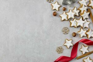 Christmas traditional German cookies, cinnamon stars with hazelnuts, decoration and tree branches on a light concrete background. Top view. Copy space. photo