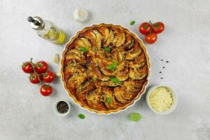 Traditional french dish ratatouille in a white baking dish on a light gray background. Healthy baked organic vegetables. Top view. photo