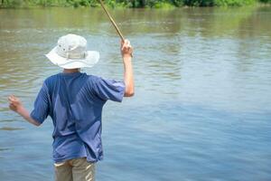 asiático joven chico en pie pescar por río participación bambú pescar varilla en hermosa agua superficie y amanecer ,estilo de vida de asiático niños, estilo de vida en rural Tailandia,concepto de vida y sostenibilidad. foto