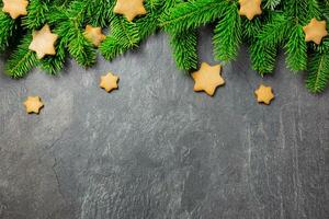Christmas traditional gingerbread stars cookies with christmas tree branches on a dark stone background. Top view. Copy space. photo