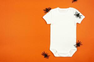 Halloween white baby girl or boy bodysuit mockup flat lay with spiders on orange background. Design onesie template, print presentation mock up. Top view. photo