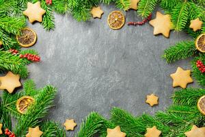 Christmas traditional gingerbread stars with decoration, spices and christmas tree branches on a dark stone background. Top view. Copy space. photo