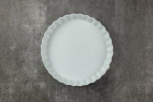 Empty white ceramic baking dish on a dark background. Food cooking background in an oven for your text. Top view. Copy space. photo