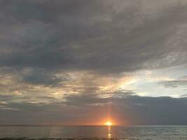 beautiful sunset in the sea under cloudy sky photo