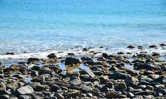 Small rocks on the beach in the sea reflect the sunlight, the sun shines on the sea in the morning. photo