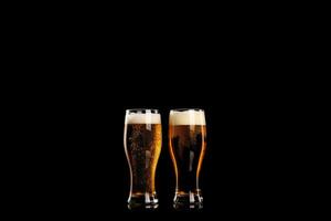 Two glasses of beer with foam isolated on black background photo