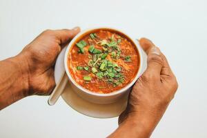 Homemade tomato soup in a white bowl with saucer. Side view isolated on a white background. photo