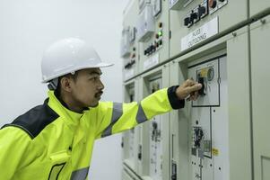 Electrical engineer man checking voltage at the Power Distribution Cabinet in the control room,preventive maintenance Yearly,Thailand Electrician working at company photo