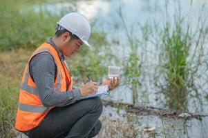 los ingenieros ambientales inspeccionan la calidad del agua, llevan el agua al laboratorio para su análisis, verifican el contenido de minerales en el agua y el suelo, verifican los contaminantes en las fuentes de agua. foto