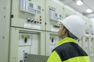 Electrical engineer man checking voltage at the Power Distribution Cabinet in the control room,preventive maintenance Yearly,Thailand Electrician working at company photo