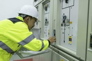 Electrical engineer man checking voltage at the Power Distribution Cabinet in the control room,preventive maintenance Yearly,Thailand Electrician working at company photo