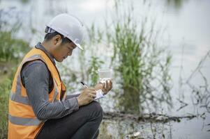 los ingenieros ambientales inspeccionan la calidad del agua, llevan el agua al laboratorio para su análisis, verifican el contenido de minerales en el agua y el suelo, verifican los contaminantes en las fuentes de agua. foto