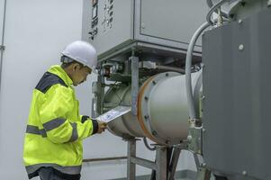 Electrical engineer man checking voltage at the Power Distribution Cabinet in the control room,preventive maintenance Yearly,Thailand Electrician working at company photo