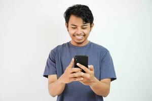 handsome smiling or happy Asian young man casual outfit in Navy t-shirt holding smart phone chatting or video call on white isolated background. photo