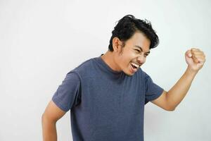 Young handsome asian man wearing casual happy and cheerful, smiling moving casual and confident listening to music over isolated white background very happy and excited doing winner gesture photo