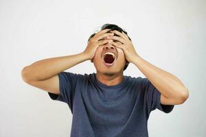 A Asian man doing wrong or mistake with both hands covering eyes isolated on white background photo