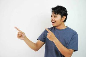 Smiling or happy handsome young Asian man with his finger pointing isolated on white background with copy space photo