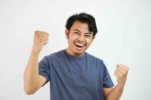 Young handsome asian man wearing casual standing over isolated white background very happy and excited doing winner gesture with arms raised, smiling and screaming for success. Celebration photo