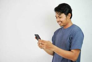 handsome smiling or happy Asian young man casual outfit in Navy t-shirt holding smart phone chatting or video call on white isolated background. photo