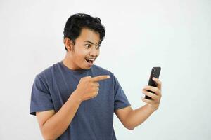 Asian man showing surprised facial expression while reading message while pointing at his phone with his finger photo