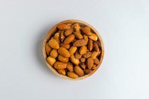 Almonds in wooden bowl. Almonds isolated on white background. photo