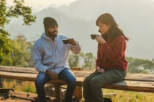 Happy traveler couple resting on mountains in sunrise with drinking coffee photo