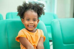 Sweet little girl outdoors with curly hair smiling sitting on chair at room photo