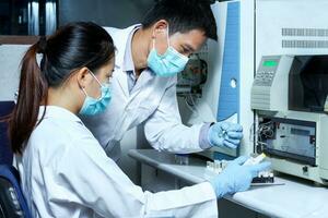 The male researcher checked the sample in the vial to analyze by Liquid Chromatography mass spectrometry LC-MS instrument in the laboratory and briefed a female scientist before analysis. photo