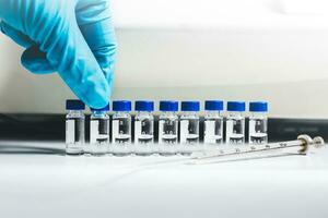Hand of the scientist pick up the vial of sample solution to analyze by Liquid Chromatography mass spectrometry LC-MS instrument in the laboratory. The LC-MS is used for scientific research. photo
