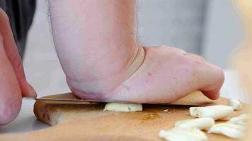 chef gebruik makend van mes naar verpletterend de vers knoflook, bereiden voor huis Koken in modern keuken, langzaam beweging video