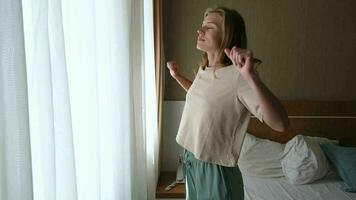 vrouw ontwaken omhoog en uitrekken in de ochtend- in hotel kamer door de venster video
