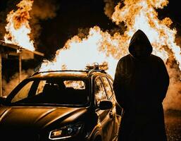 photo of man wearing hoodie jacket in front of burning car cover with fire, generative AI