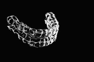 Invisible aligners retainers of teeth lie on the mirror on a black and white photograph photo