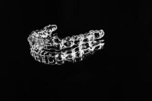 Invisible aligners retainers of teeth lie on the mirror on a black and white photograph photo