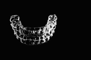 Invisible aligners retainers of teeth lie on the mirror on a black and white photograph photo