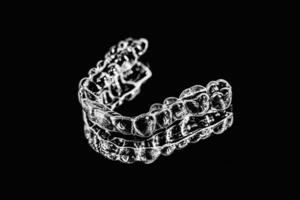 Invisible aligners retainers of teeth lie on the mirror on a black and white photograph photo