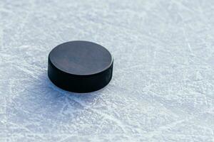 black hockey puck lies on ice at stadium photo