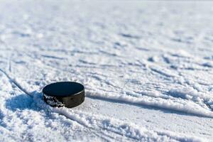 black hockey puck lies on ice at stadium photo